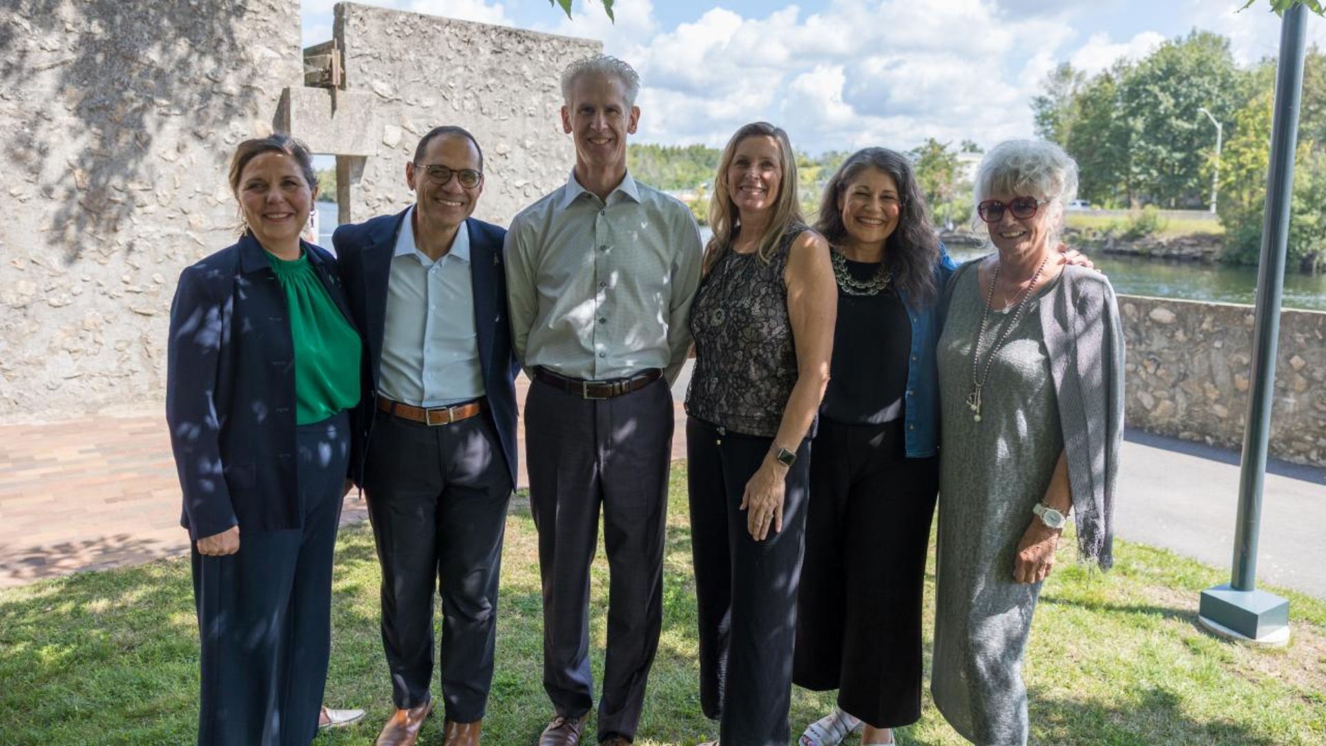 Photo of six people standing together with river in the background