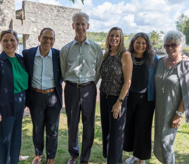 Photo of six people standing together with river in the background