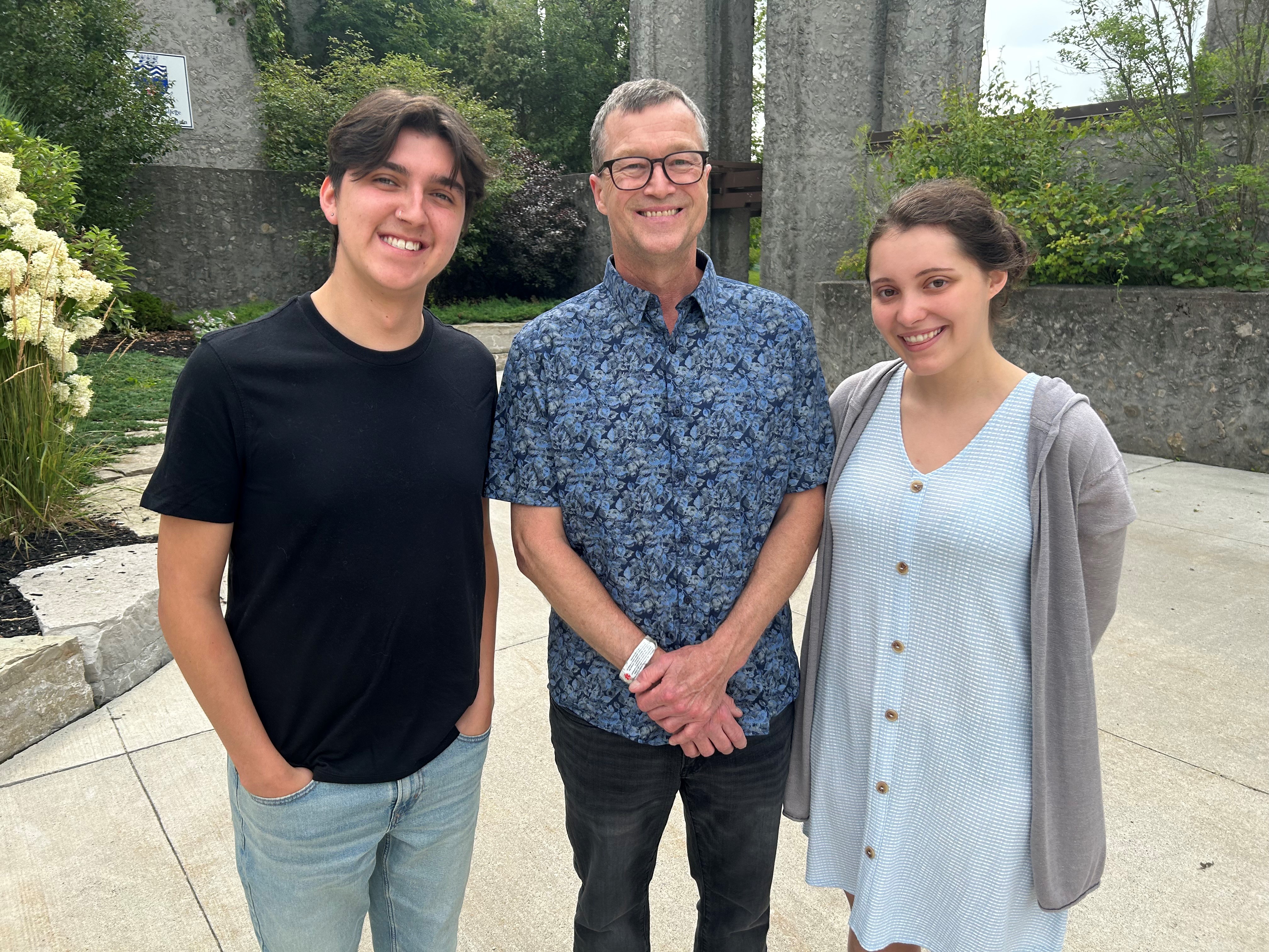 Brad Holland standing with two students