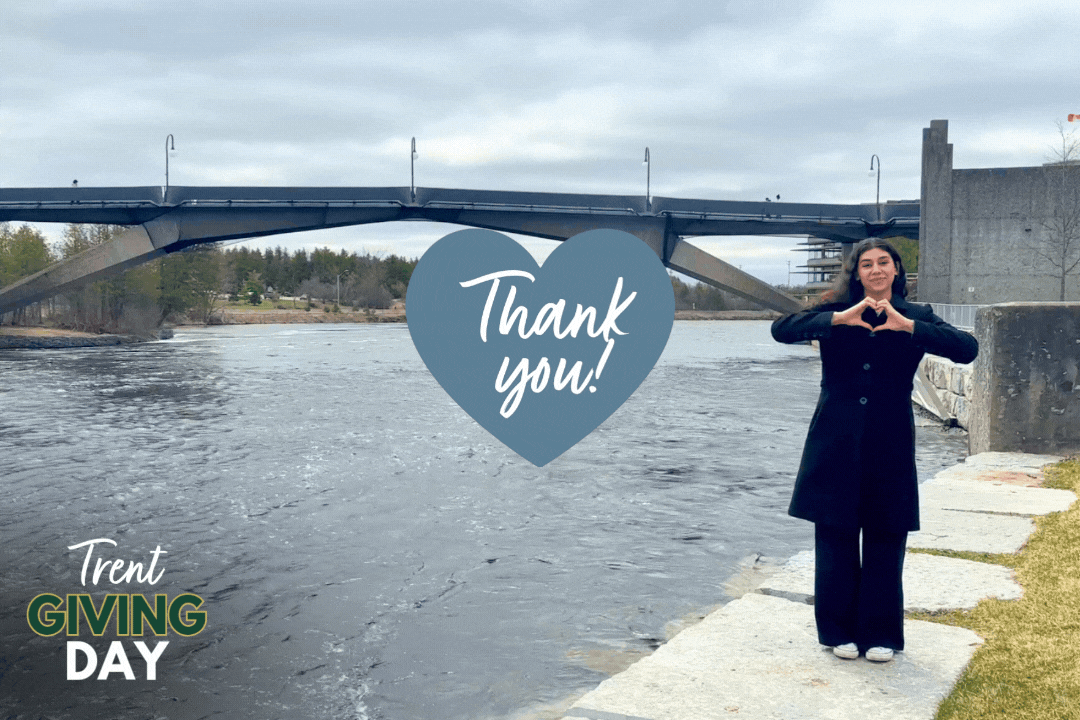 A girl standing next to the river doing a heart sign
