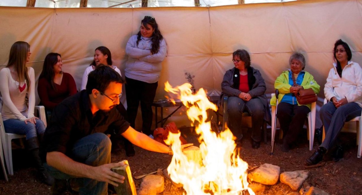 A bunch of people gathering around the fire pit